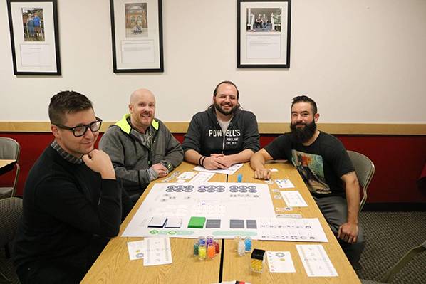 Group of men around a table with game design papers in front of them