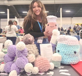 Kristine standing behind a table of crochet chemistry plushies