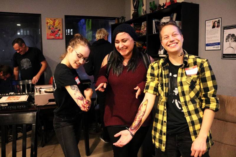 Ambassadors Dara Niketic (left) and Amanda Cooper (right) display the handiwork of tattoo artist Krystal Johnson (center).