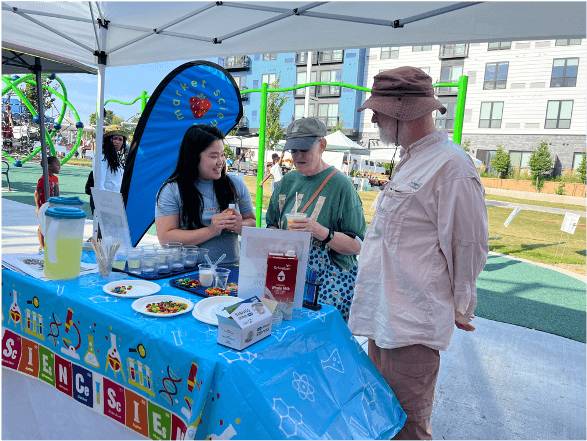 three individuals chatting at a farmers market booth